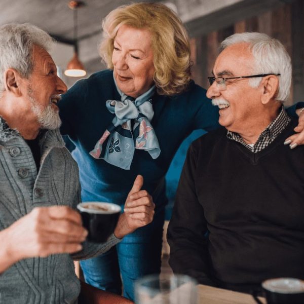 SMAF 1 Deux hommes boivent un café et sourient a une femme qui les enlace par les épaules.